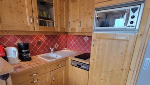 Eine kleine Küche mit Holzausstattung, einer Mikrowelle, einem Spülbecken und einer Kaffeemaschine.