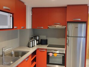 A kitchen with a stainless steel refrigerator, a microwave, and a stove.