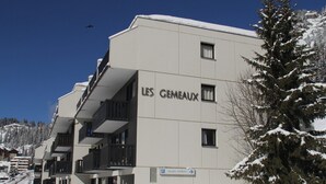 Ein mehrstöckiges Gebäude mit dem Namen "LES GHEMAUX", mit Balkonen und einem Schild, das "accès piétons" für Fußgängerzugang anzeigt.