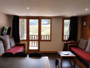 A room with two seating areas, a table, and a television.