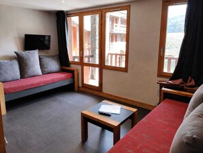 A room with a sofa, a small table, and a window with a view of buildings.