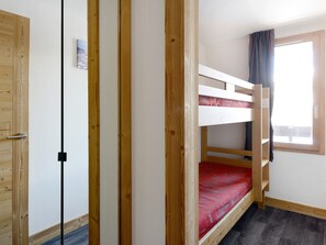 A bunk bed with a red mattress, a wooden wardrobe, and a window with curtains. - Renovated 2017 Apartment, 3 rooms, 7 pers, wellness space (La Plagne Montchavin Les Coches)