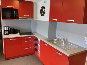 A kitchen with red cabinets, a microwave, a coffee maker, and a toaster. - Renovated 2017 Apartment, 3 rooms, 7 pers, wellness space (La Plagne Montchavin Les Coches)
