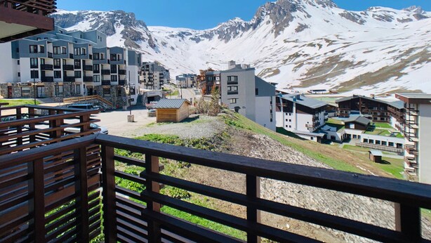 Une ville de montagne avec des bâtiments modernes, une terrasse en bois et, en arrière-plan, des montagnes enneigées.
