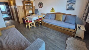 Un salon chaleureux avec un canapé en bois, une table à manger avec des chaises et un petit meuble en bois.