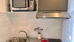 Une cuisine équipée d’un évier en acier inoxydable, d’un four à micro-ondes, d’une cuisinière et d’une hotte aspirante.