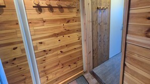 Un couloir intérieur en bois, avec une porte et un porte-manteau.