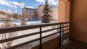 A balcony with a view of a snow-covered parking lot and buildings in the background. - Cozy studio with ski shuttle and private locker - 4 guests (La Salle-les-Alpes)
