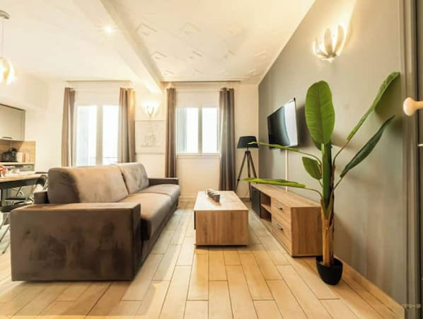 A modern living room with a sofa, coffee table, and a large plant. - ZEN&COSY#PARKING#WIFI#NETFLIX#TRAIN STATION#SLEEPNTRIP (Béziers)