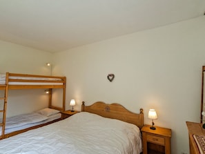 A bunk bed room with a single bed, bedside tables with lamps, and a heart-shaped decoration on the wall.
