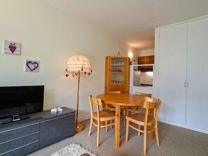 A compact living space with a flat-screen TV, a dining table with chairs, a floor lamp, and a wardrobe. - Bright apartment at the foot of the slopes with free WIFI (Flaine)