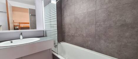 Un baño moderno con una bañera blanca, un lavabo y un espejo grande.