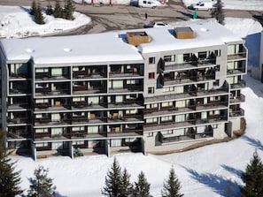 Een meerlaags hotel met balkons, een parkeerplaats en besneeuwde omgeving.