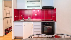A compact kitchen with white cabinets, a red-tiled backsplash, a stainless steel sink, a dishwasher, and a built-in oven. - Renovated studio for 4, near slopes in Flaine (Flaine)