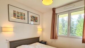 Un dormitorio con una cama, dos mesitas de noche, un cabecero, dos lámparas de pared y dos cuadros enmarcados.