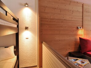 A hotel room with a bunk bed, a wooden wall, and a small table with magazines. - Renovated studio at slopeside - Pets allowed (Plagne Bellecôte)