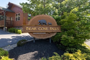 A wooden sign with a bear and a waterfall, indicating the name of the location. - Hummingbird Hill Vista- Pool HotTub View (Pigeon Forge)