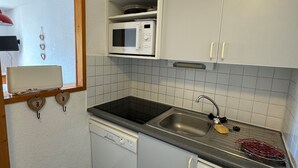 A compact kitchen with a microwave, sink, and dishwasher.
