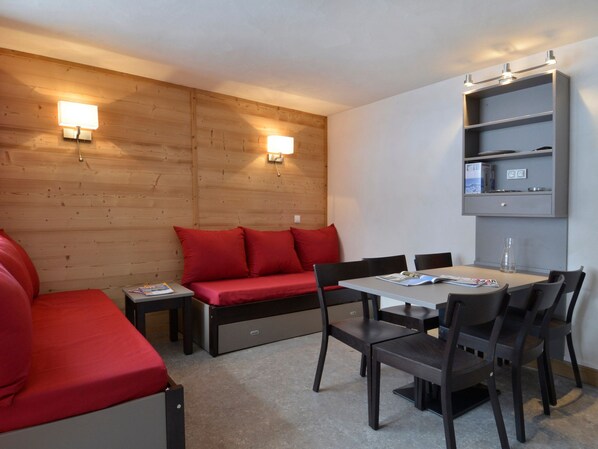 Una habitación moderna con sofá, una mesa de comedor con sillas y una estantería empotrada.