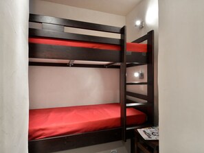 Una cama litera con colchón rojo y estructura de madera.