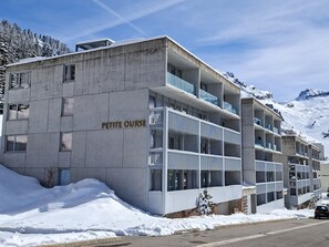 A multi-story building with a sign reading 'PETITE OURSE,' surrounded by snow and mountains. - New studio for 4 in Flaine center with balcony (Flaine)