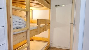 Une chambre avec un lit superposé, un plafond en bois et une porte blanche.