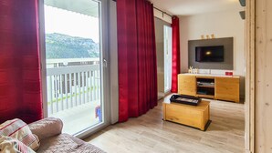 Un salon spacieux doté d’une grande porte-fenêtre coulissante donnant sur un balcon, d’un meuble TV en bois et d’un canapé.