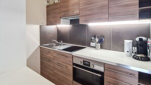Une cuisine moderne avec des meubles en bois, des appareils électroménagers en acier inoxydable et un four encastré.