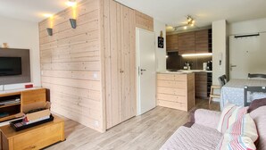 Un espace de vie compact comprenant un coin cuisine, un coin repas et un téléviseur.