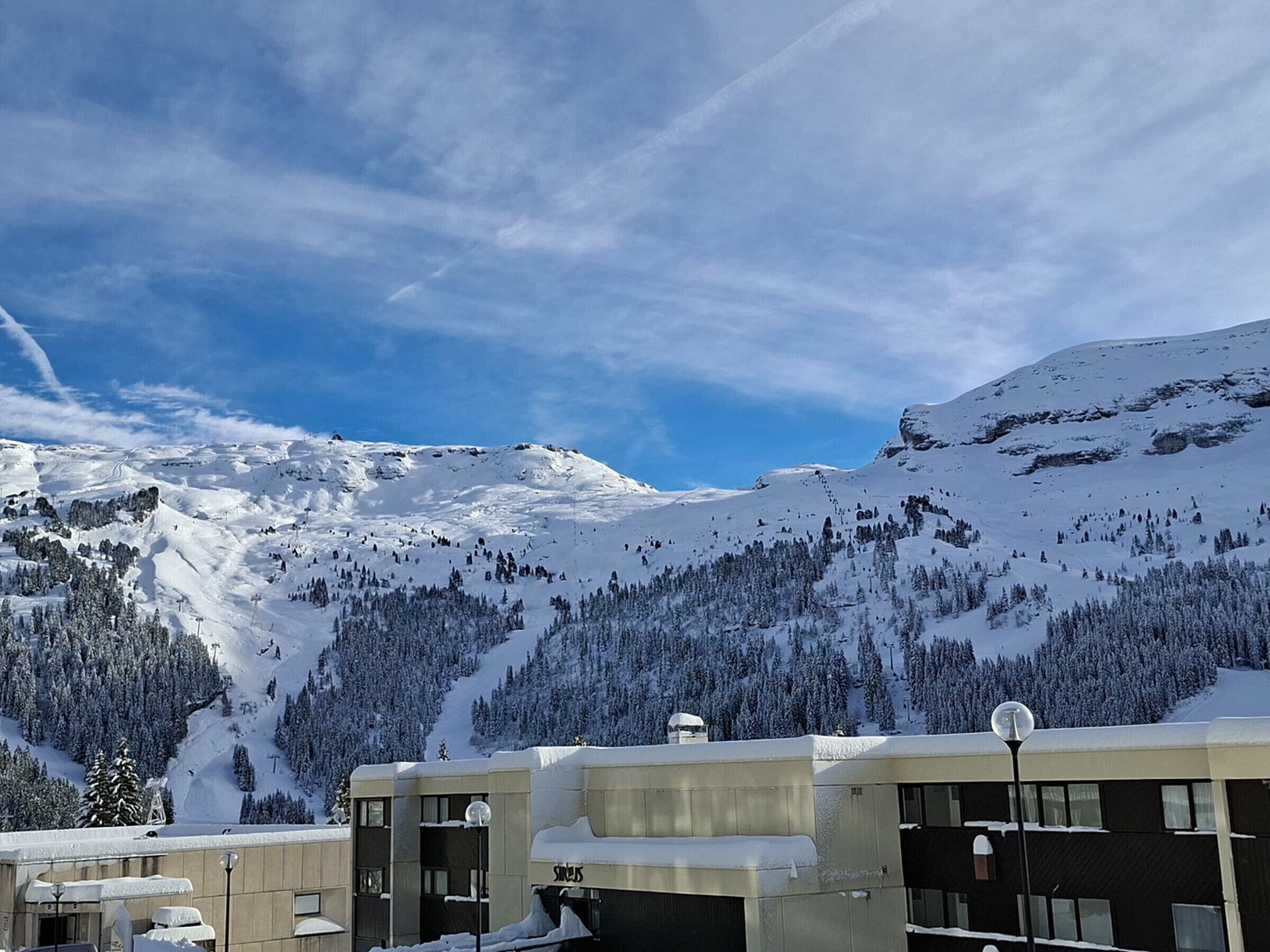 Ett hotell med ett snötäckt tak och utsikt över ett snöigt bergskedja.