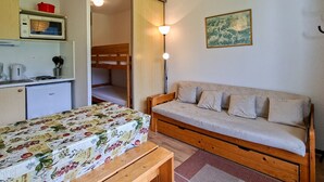 A compact room with a bunk bed, a sofa bed, a small kitchenette, and a dining table. - Comfortable studio with balcony in Flaine center (Flaine)