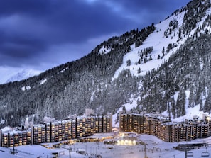 Ein schneebedecktes Resort mit mehreren Hochhäusern, Skiliften und einer Bergkulisse im Hintergrund.