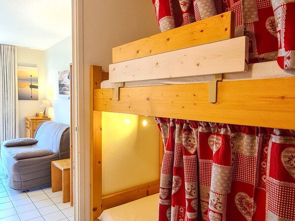 Une chambre avec un lit superposé, une petite table de chevet, une chaise et un canapé dans la pièce adjacente.