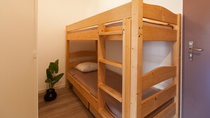 Een stapelbed met twee niveaus, een kleine potplant en een deur met een hendel.
