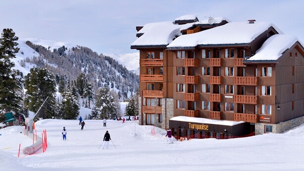 A multi-story hotel with a ski slope in the background. - Apartment with balcony and direct slope access, pets allowed (Belle Plagne)