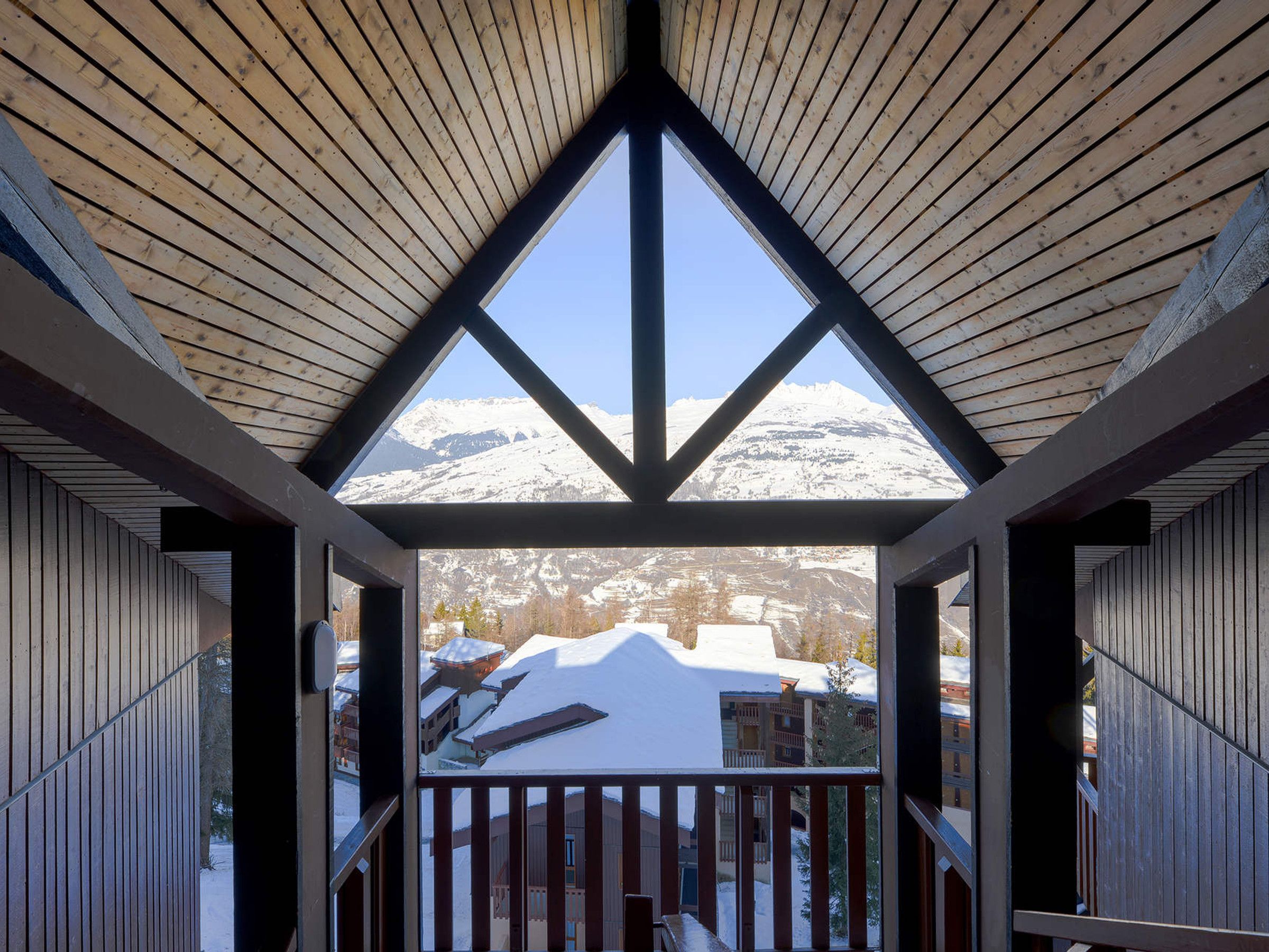 A wooden balcony with a view of snow-covered mountains.