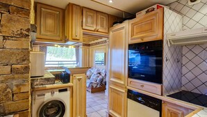 A compact kitchen with wooden cabinets, a Bosch oven, a Bosch dishwasher, and a washing machine.