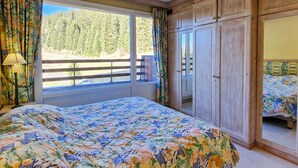 A bedroom with a large bed, a wardrobe, and a window with curtains.