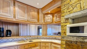 A kitchen with wooden cabinets, a stone accent wall, and a built-in microwave.