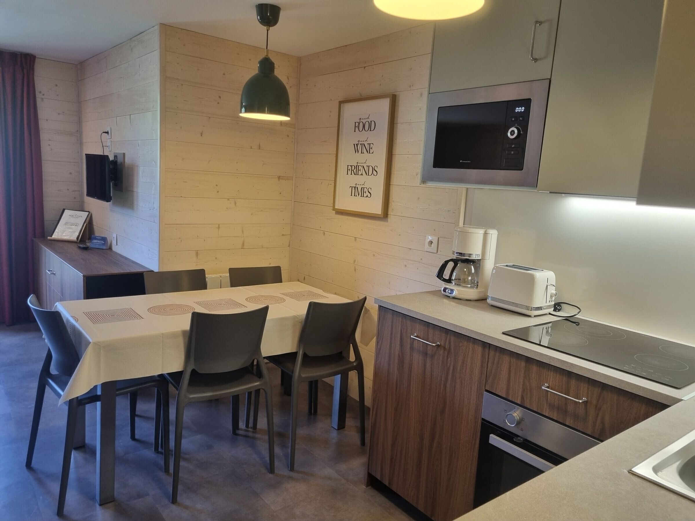 Una cocina moderna con comedor, paredes de madera, cafetera y microondas.