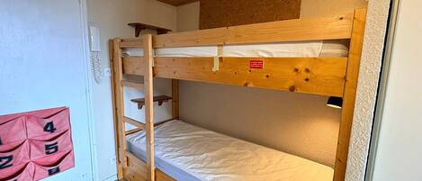 A bunk bed with a ladder, a small shelf, and a red sign with numbers.