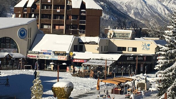Un immeuble à étages, une station de ski en arrière-plan et un paysage enneigé.