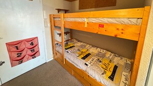 Un lit superposé avec un lit inférieur, une porte sur laquelle est affiché un tableau de chiffres et un plafond en bois.