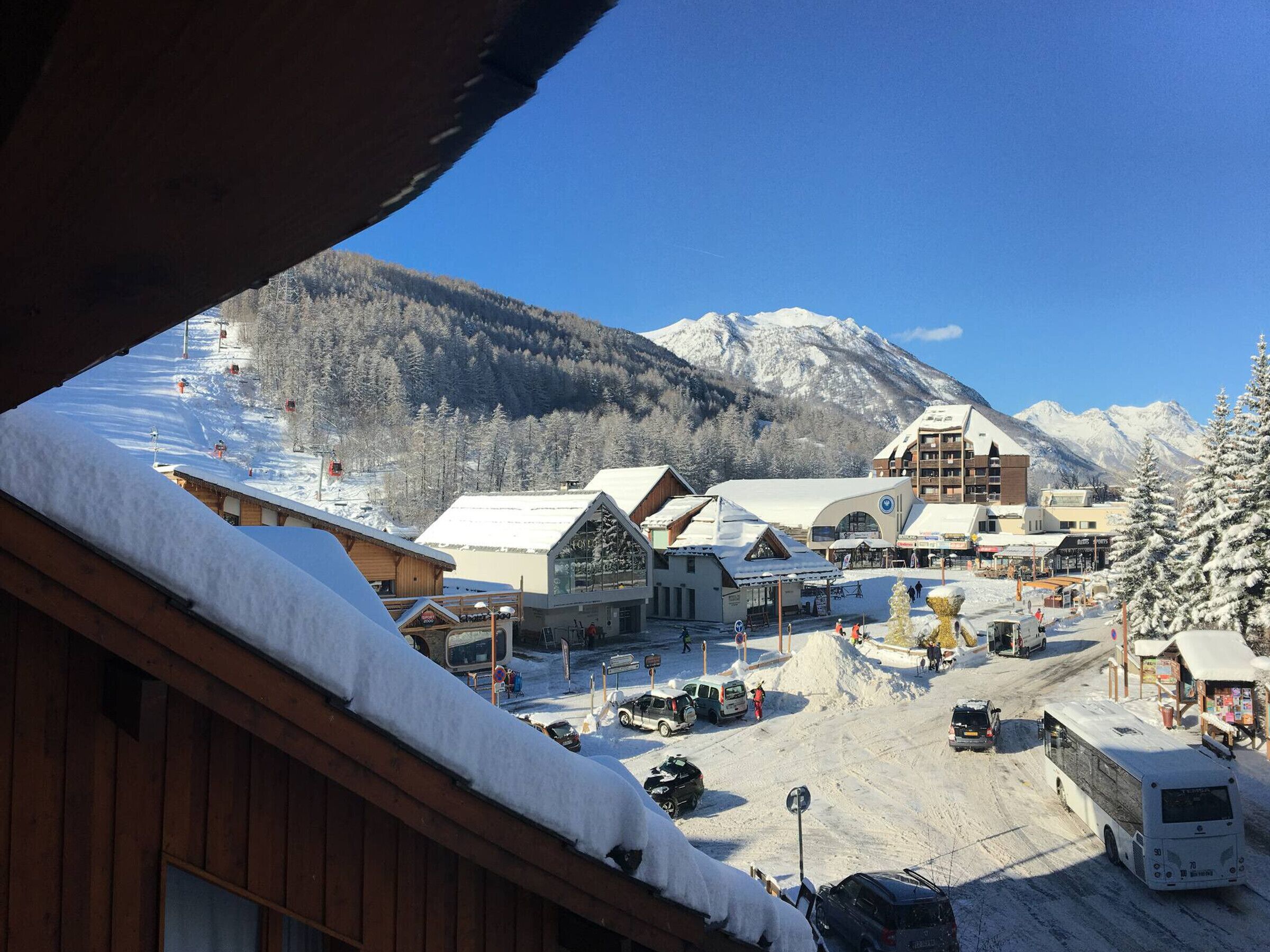 A snow-covered town with buildings, a ski lift, and mountains in the background.