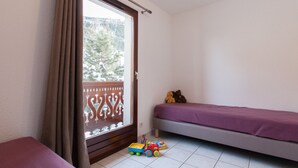A bedroom with a bed, a window with curtains, a toy truck, and a teddy bear. - Bright triplex chalet, shuttle to slopes, Wifi, pets allowed (La Salle-les-Alpes)