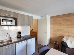 Compact kitchen with modern appliances, microwave, coffee maker, and dishwasher. Features a dining area with a simple table and chairs.