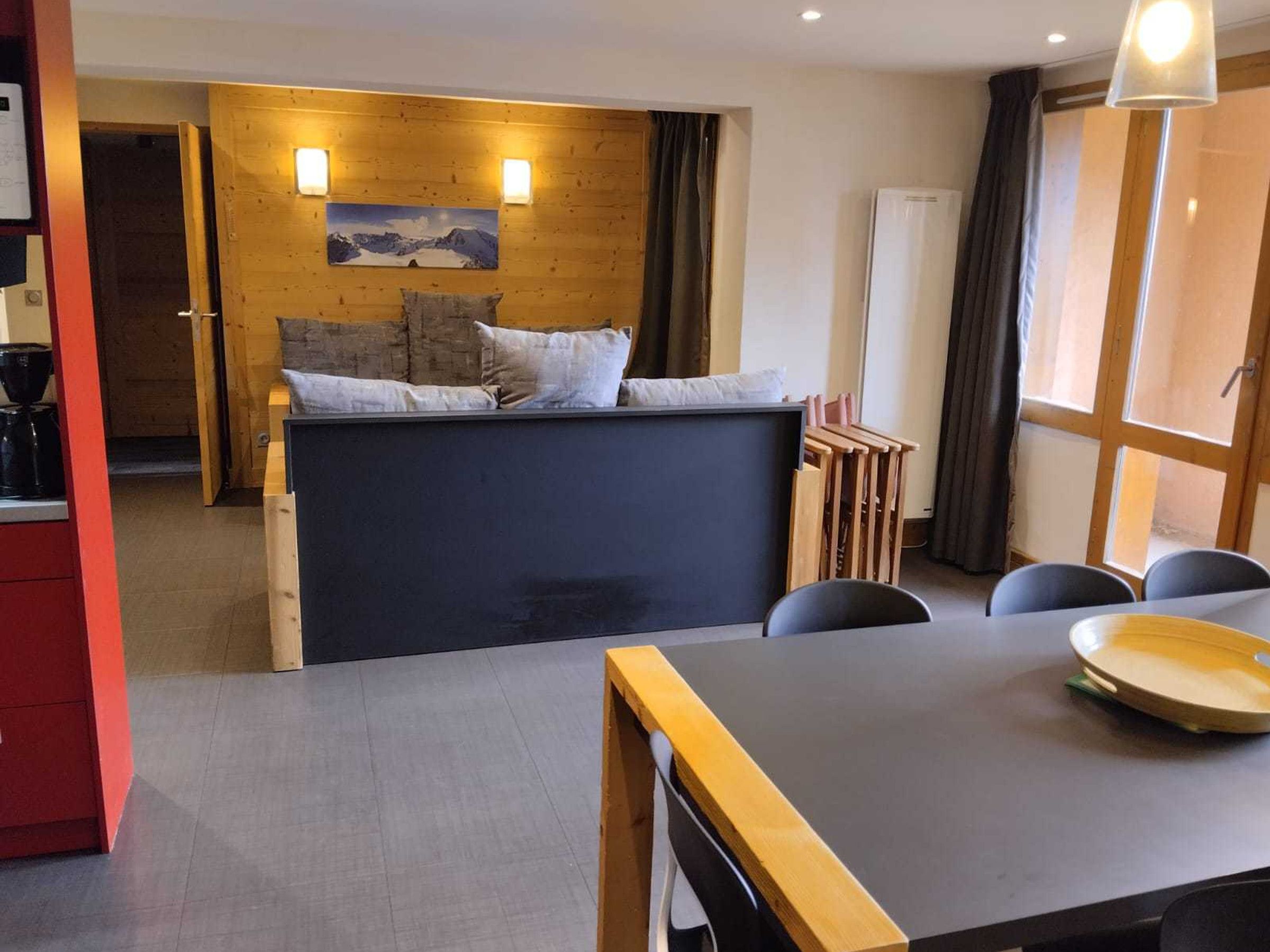 A modern room with a bed, a dining table, and a view of a mountain landscape.