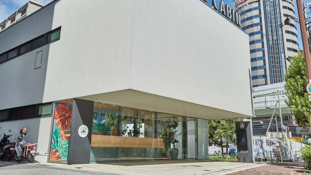 A modern building with a prominent 'First Cab' sign, large windows, and a colorful mural on the side. - First Cabin Nishi Umeda (Osaka)