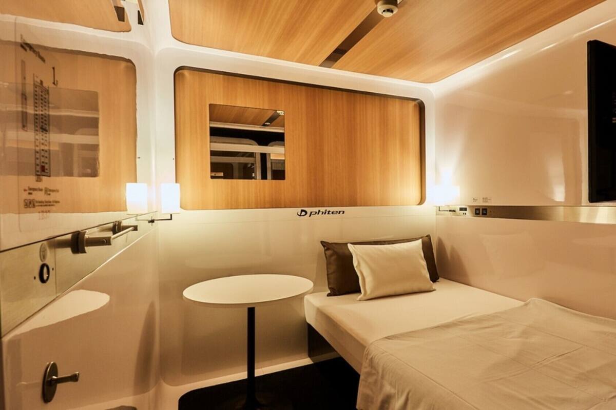 Un compartiment de train compact et moderne, équipé d’un lit, d’une petite table et d’un miroir.