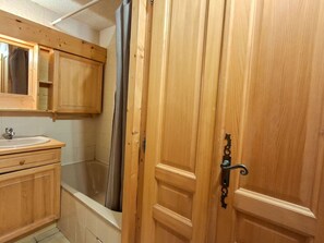Ein Badezimmer aus Holz mit Waschbecken, Spiegel und Duschvorhang.